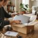 Personne emballant un ordinateur portable dans un carton pour le revendre en ligne