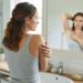Femme de dos vérifiant la peau lisse de son épaule dans un miroir de salle de bain